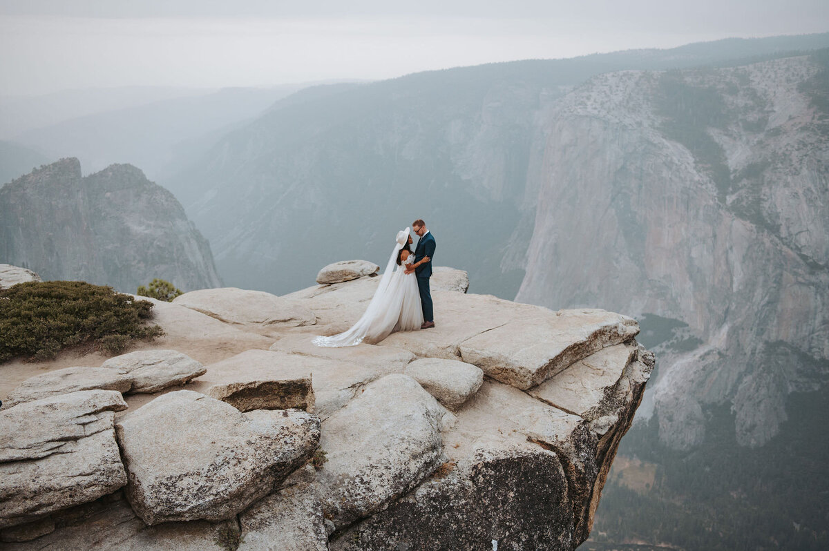 couple embracing on rock at Taft Point overlooking Yosemite Valley