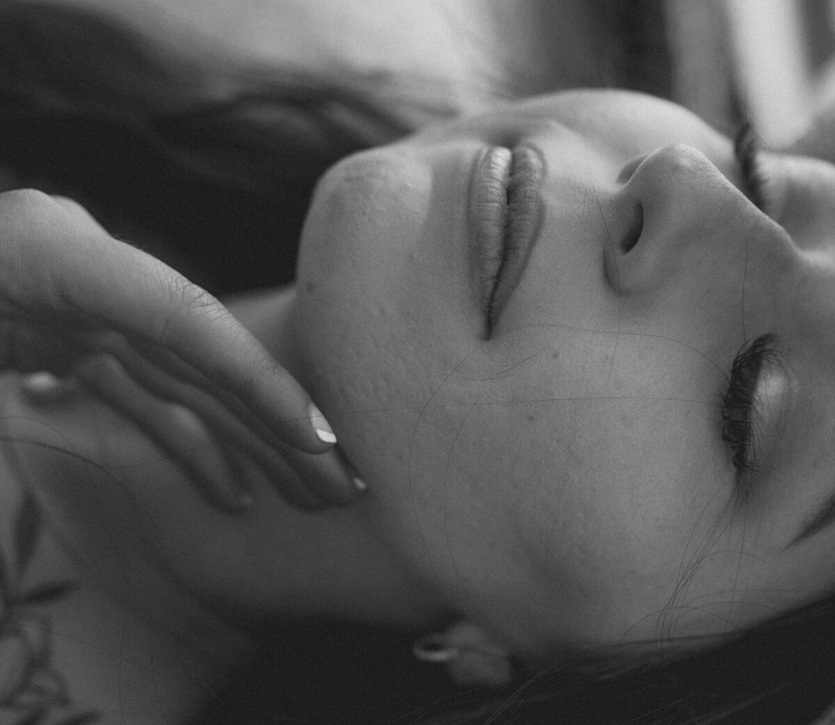 woman with dark hair gently touches her face for a photo at the Oregon Coast