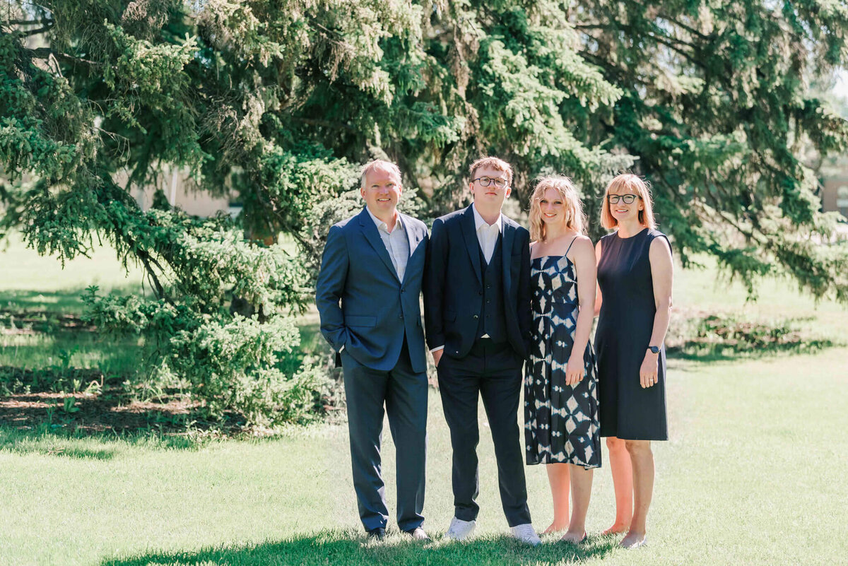 A young graduate standing with his parents and sister. 