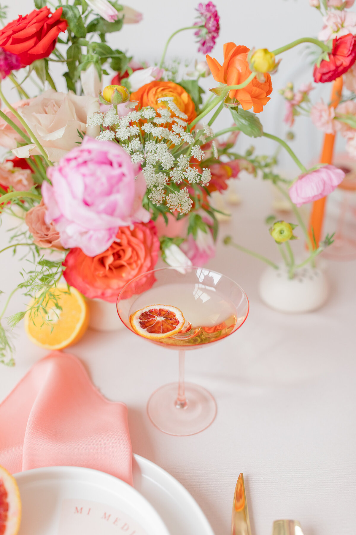 colorful place setting with blood orange and pink rose in a glass