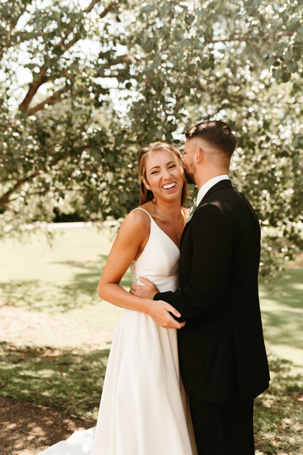 Groom whispering in bride's ear and making her laugh