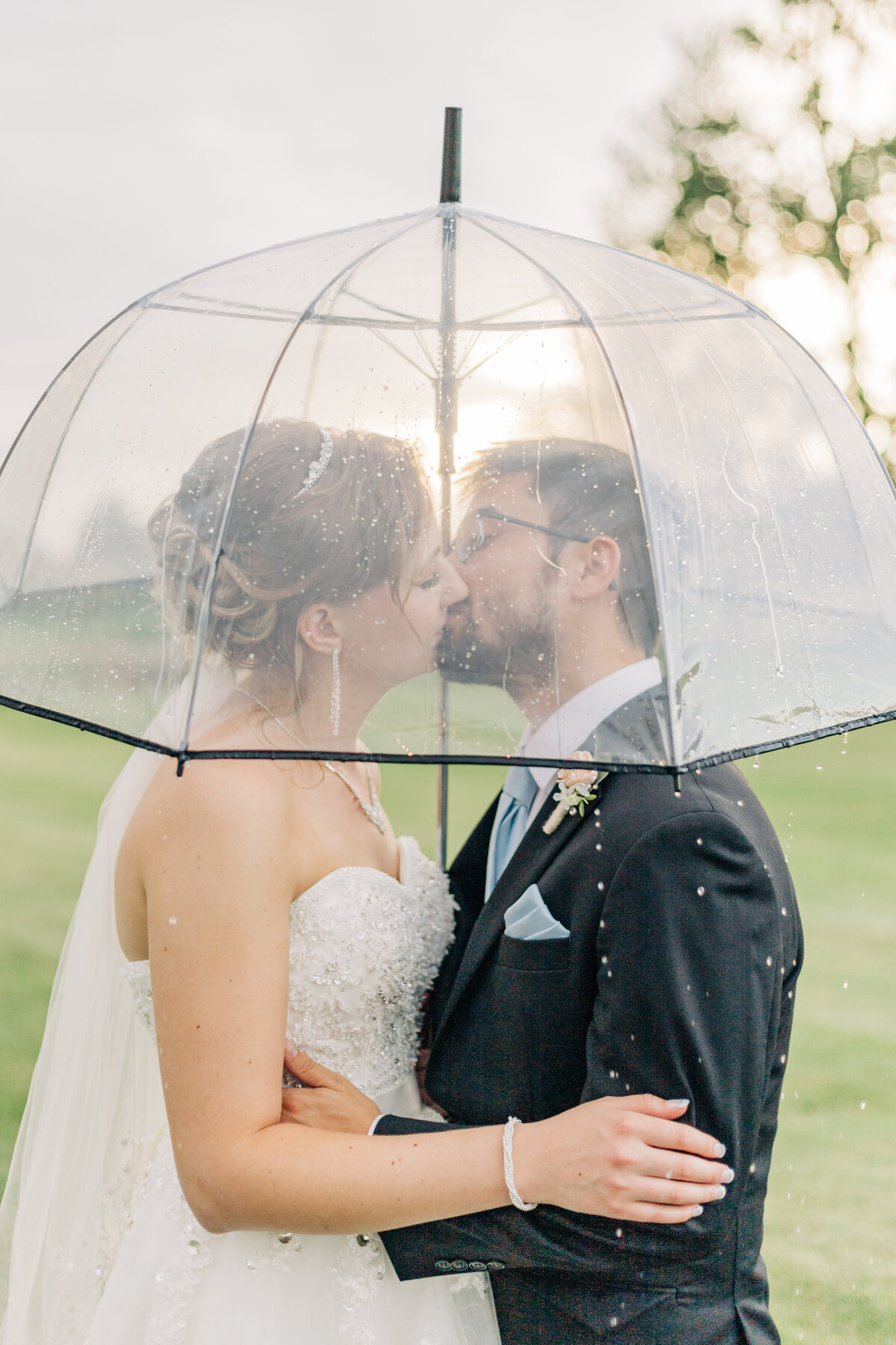 bride and groom kissing under umbrella