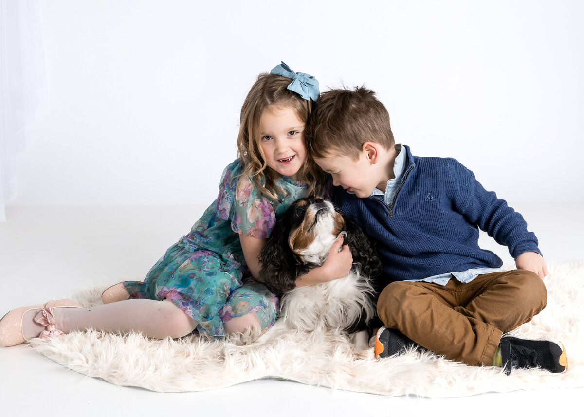 Lifestyle portrait of siblings hugging family dog at Allison Reilly's Union County, NJ photo studio.
