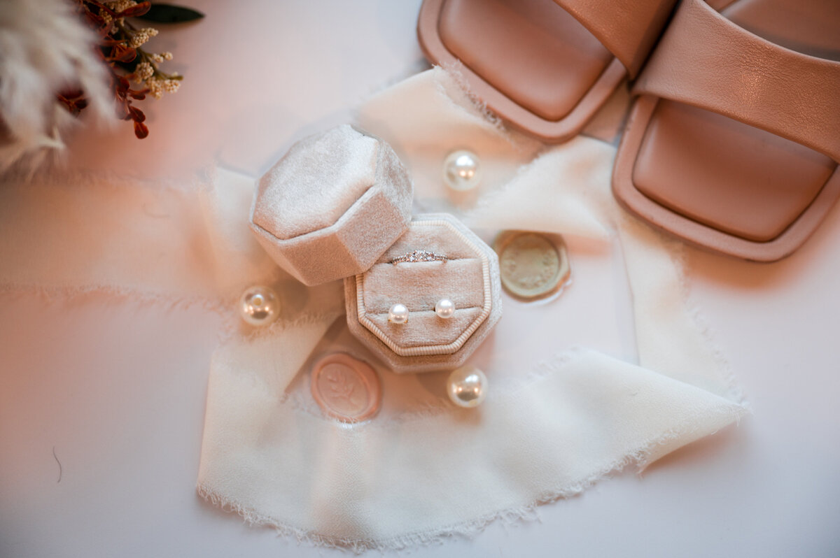 wedding rings in a white box, surrounded by white ribbon and brides shoes 