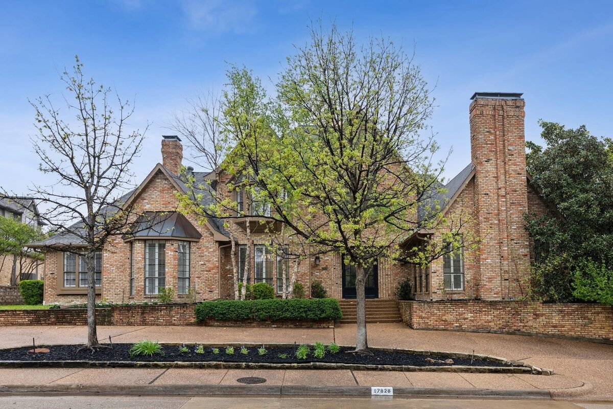 North Dallas brick home with manicured front yard, double chimneys, and custom architecture ideal for homebuyers seeking elegance and space.