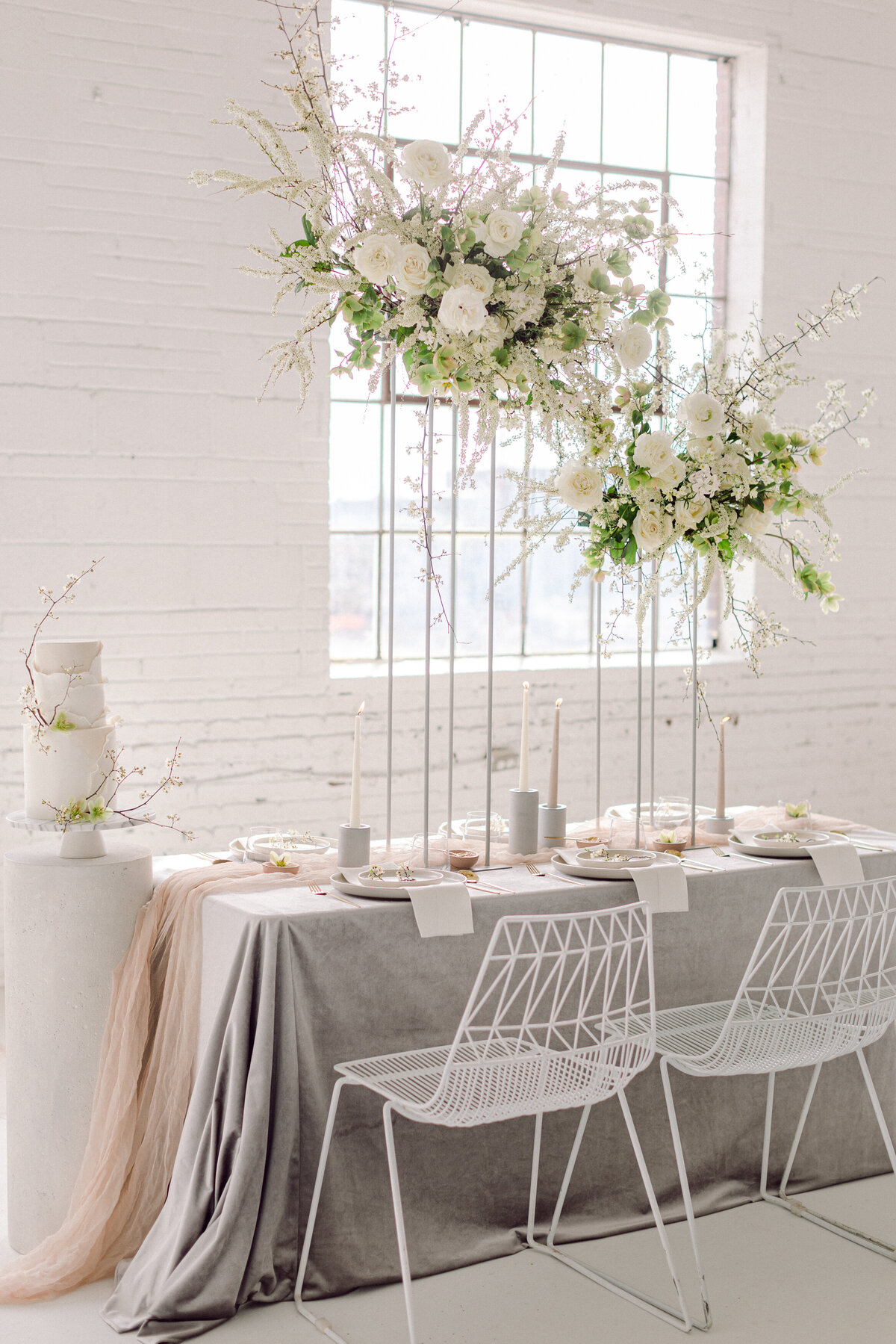 Airy centrepieces of white flowers and greenery are elevated above a table for a wedding at L’Eloi.
