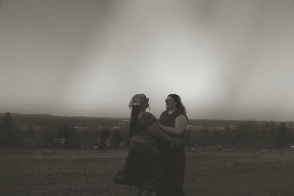 A couple with their arms around each other in a field.