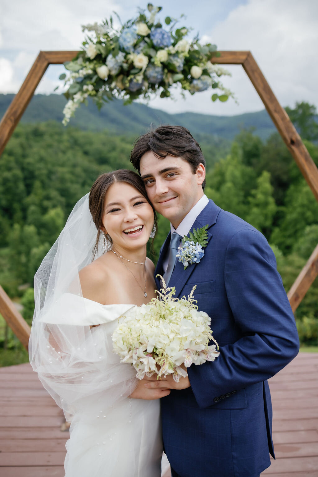 wedding photographers gatlinburg tn photographs wedding portrait with bride and groom smiling in front of their wedding arch at Mountain Mist wedding venue in the smokies 
