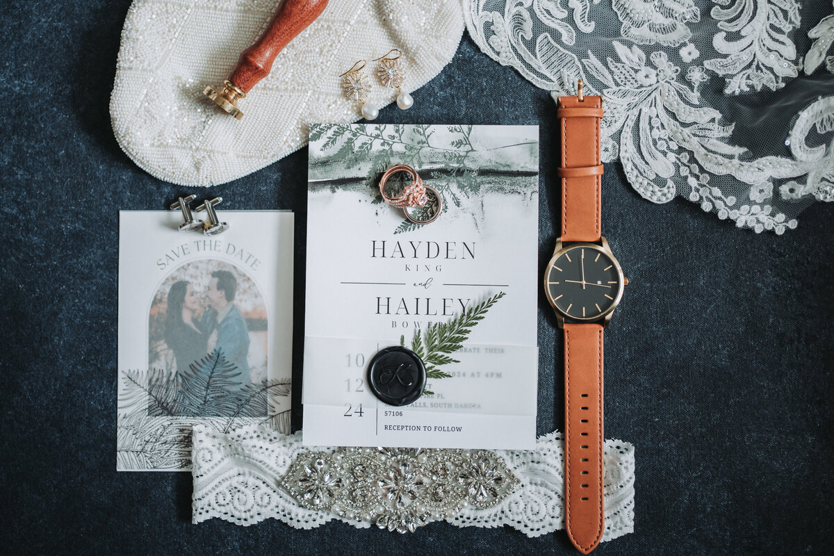 Couples beautiful flat lay with a watch, invitation, and other items from the wedding day.