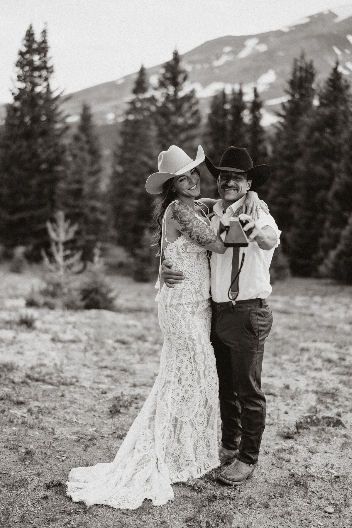 Western-style wedding couple in cowboy hats posing with mountain backdrop in Hoosier Pass.