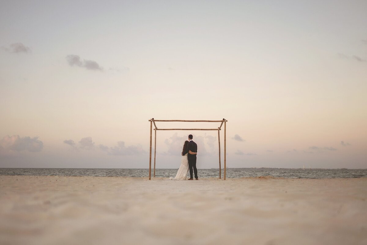 Bride and groom under wedding gazebo on beach after decorations have been removed in Cancun