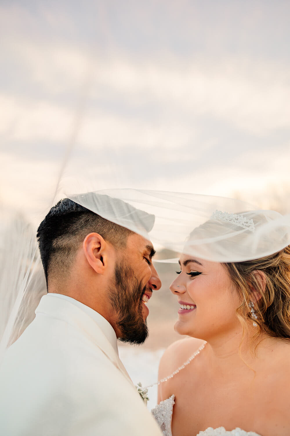 bride and groom smiling at each other under vail. Photographed by Michelle Betz Photography wedding photographer