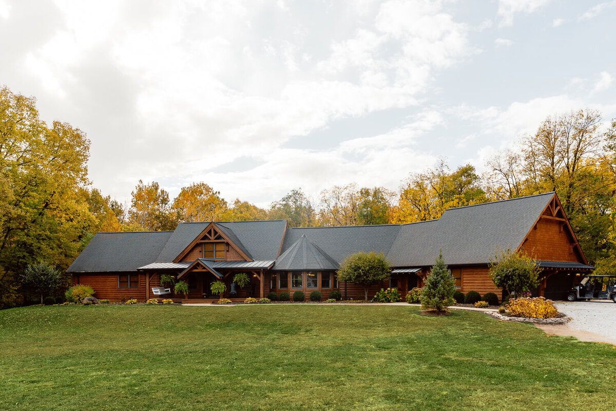 Front view of a large wooden lodge with autumn foliage