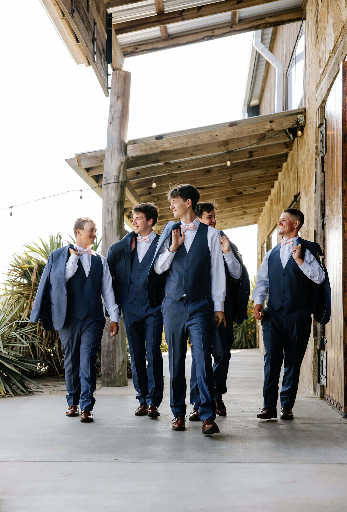groom and groomsmen in navy suits walking to wedding chapel on wedding day