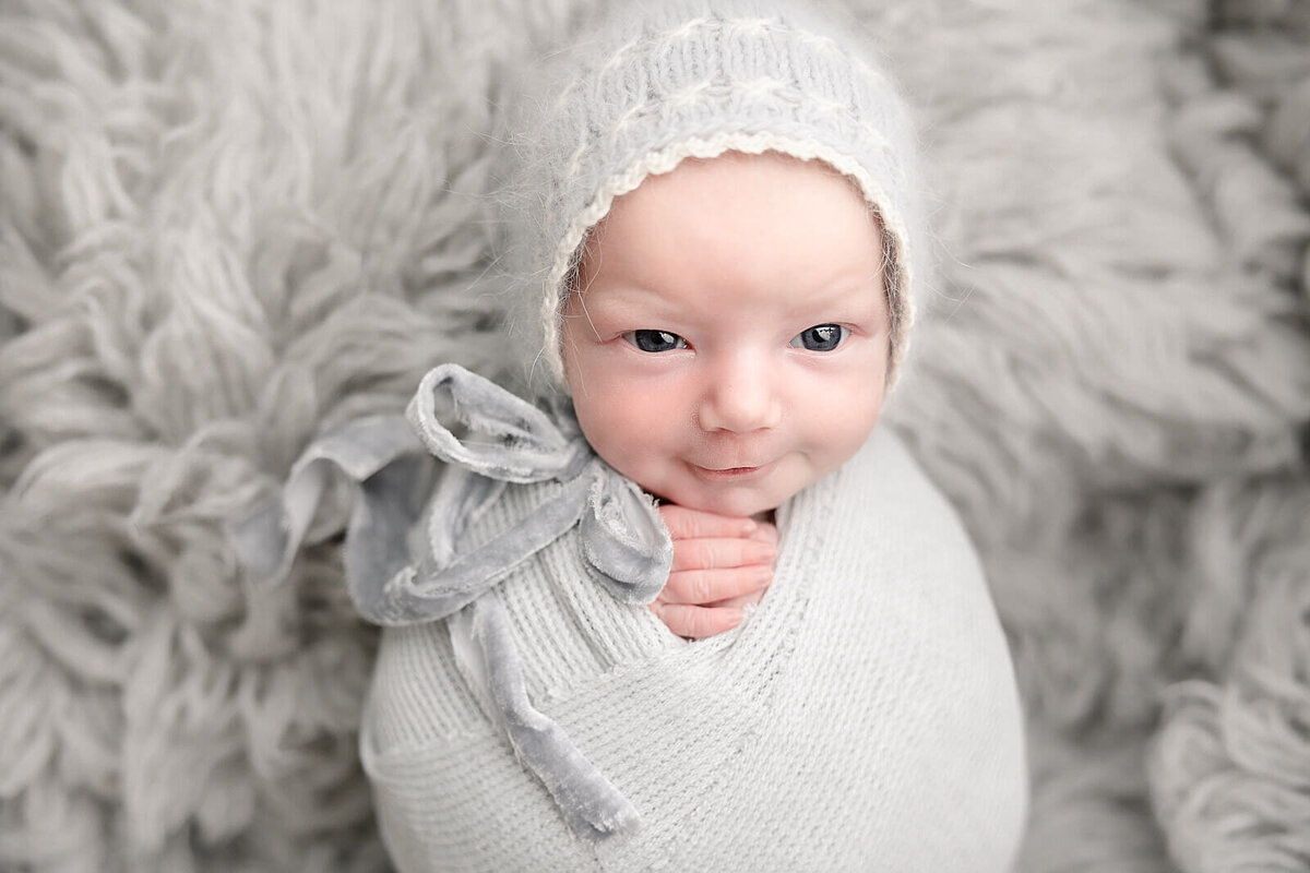 smiling baby girl in grey bonnet in portland studio