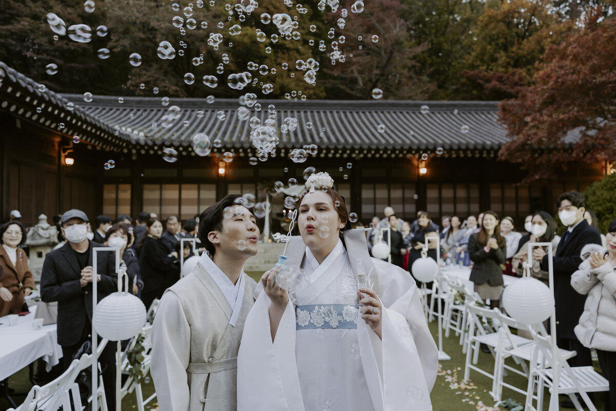 bride and groom blowing bubbles at their outdoor wedding in seoul