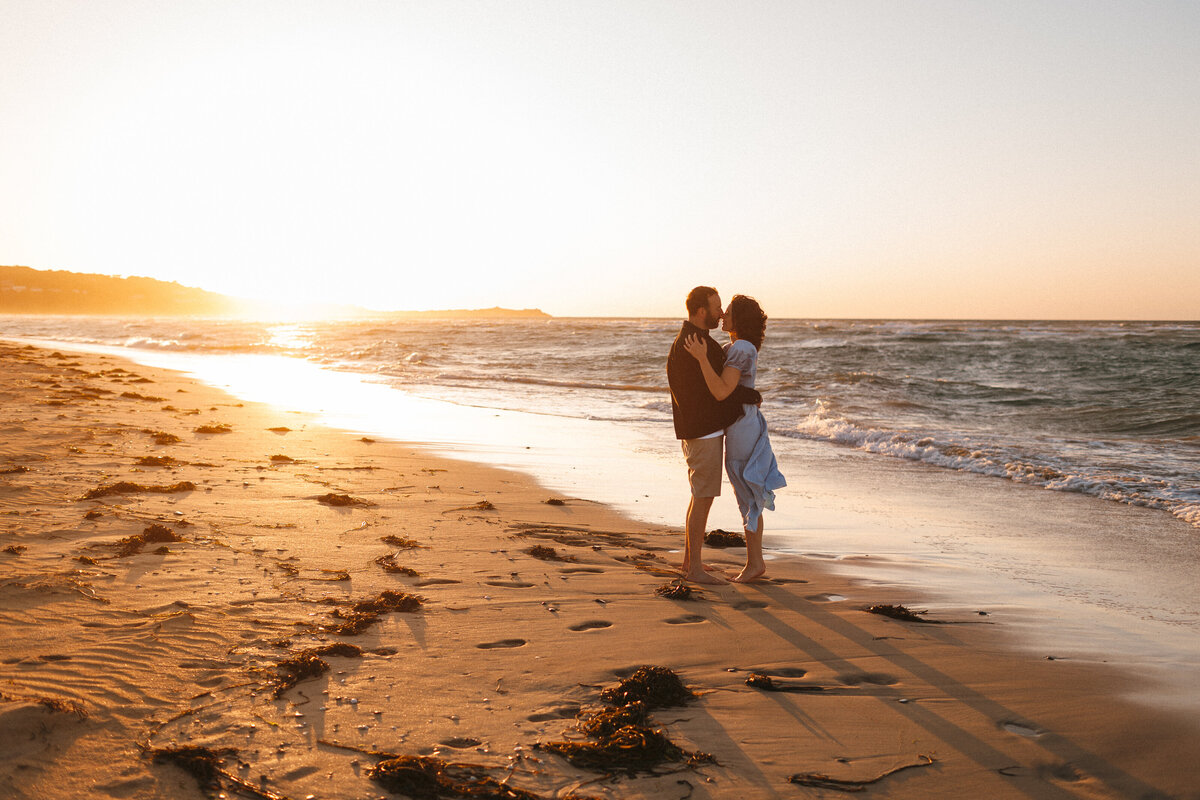 Couple kiss by the sea in Cornwall