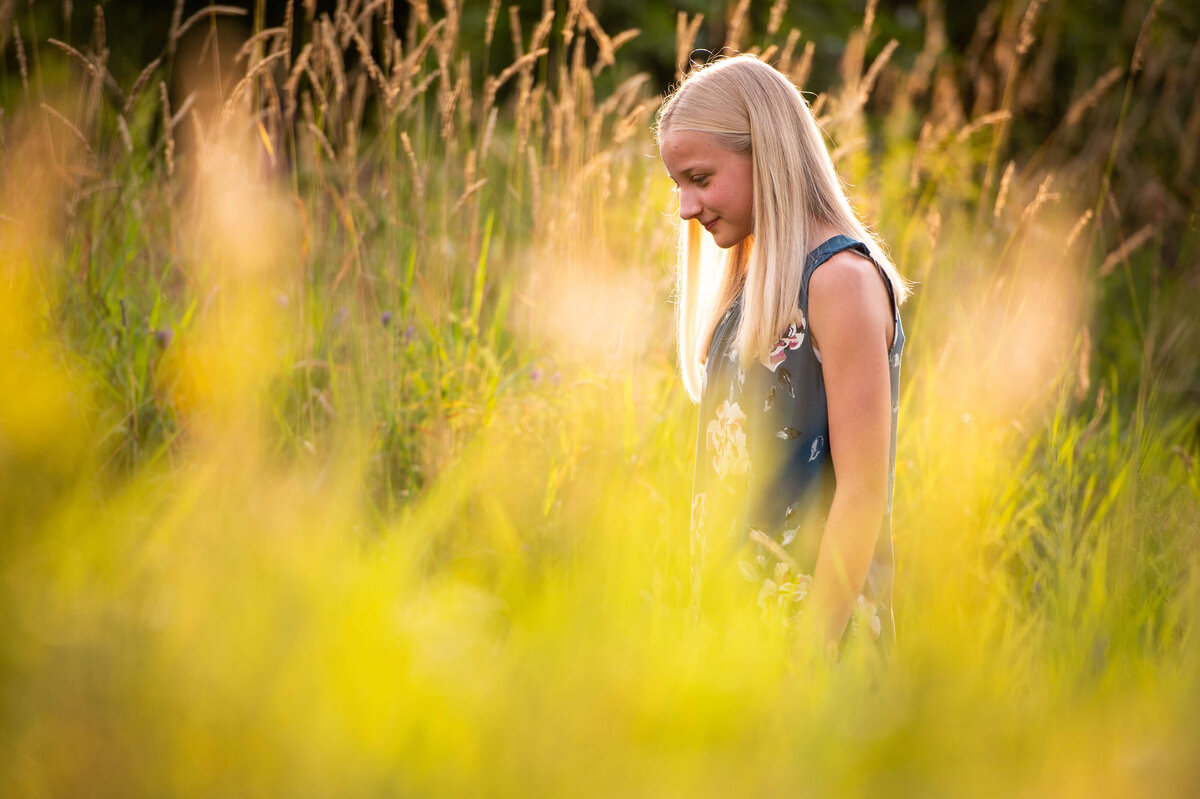 a teenage girl walking in a grassy field at sunset captured by Ottawa Family Photographer JEMMAN Photography