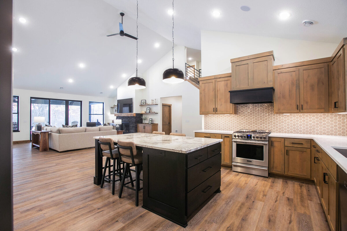 Open kitchen with dark cabinets, large island, and quartz countertops in an Elk River custom home