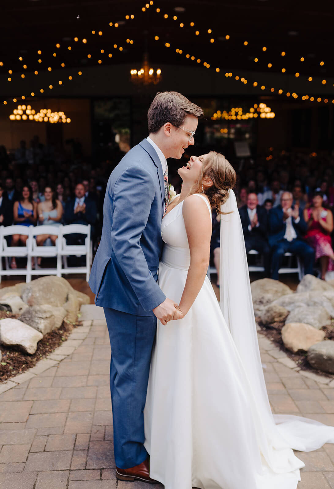 Bride and groom standing together laughing in front of wedding guests at Oswego wedding, NY