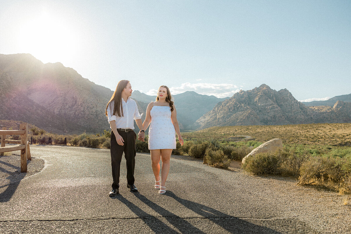 Engaged couple walking on empty road with Nevada mountains in the back
