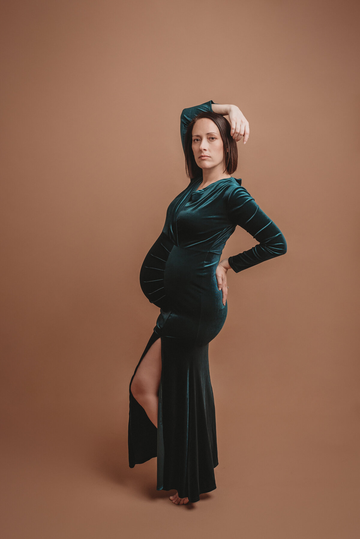30 weeks pregnant woman wearing green velvet maternity dress posing for portraits