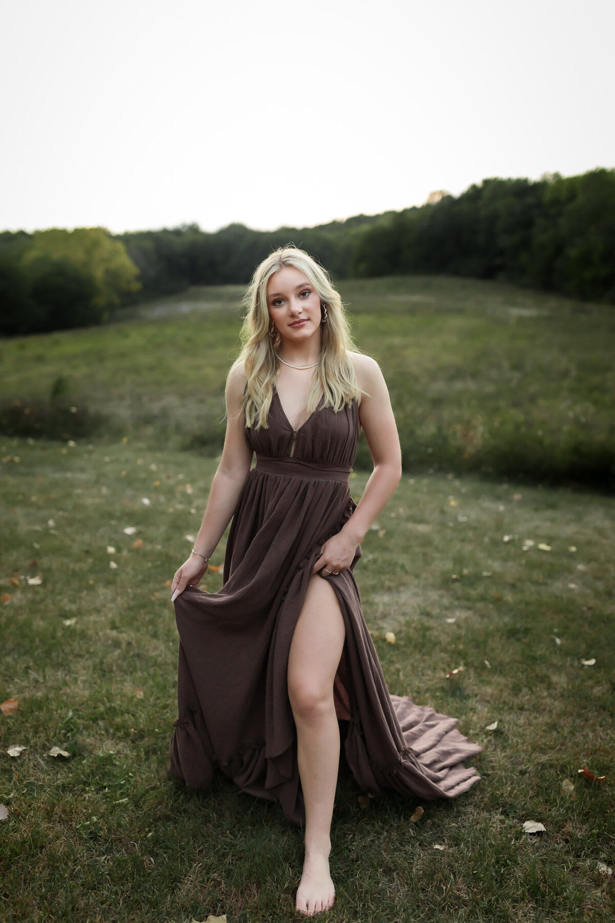 senior wearing brown sleeveless gown in field