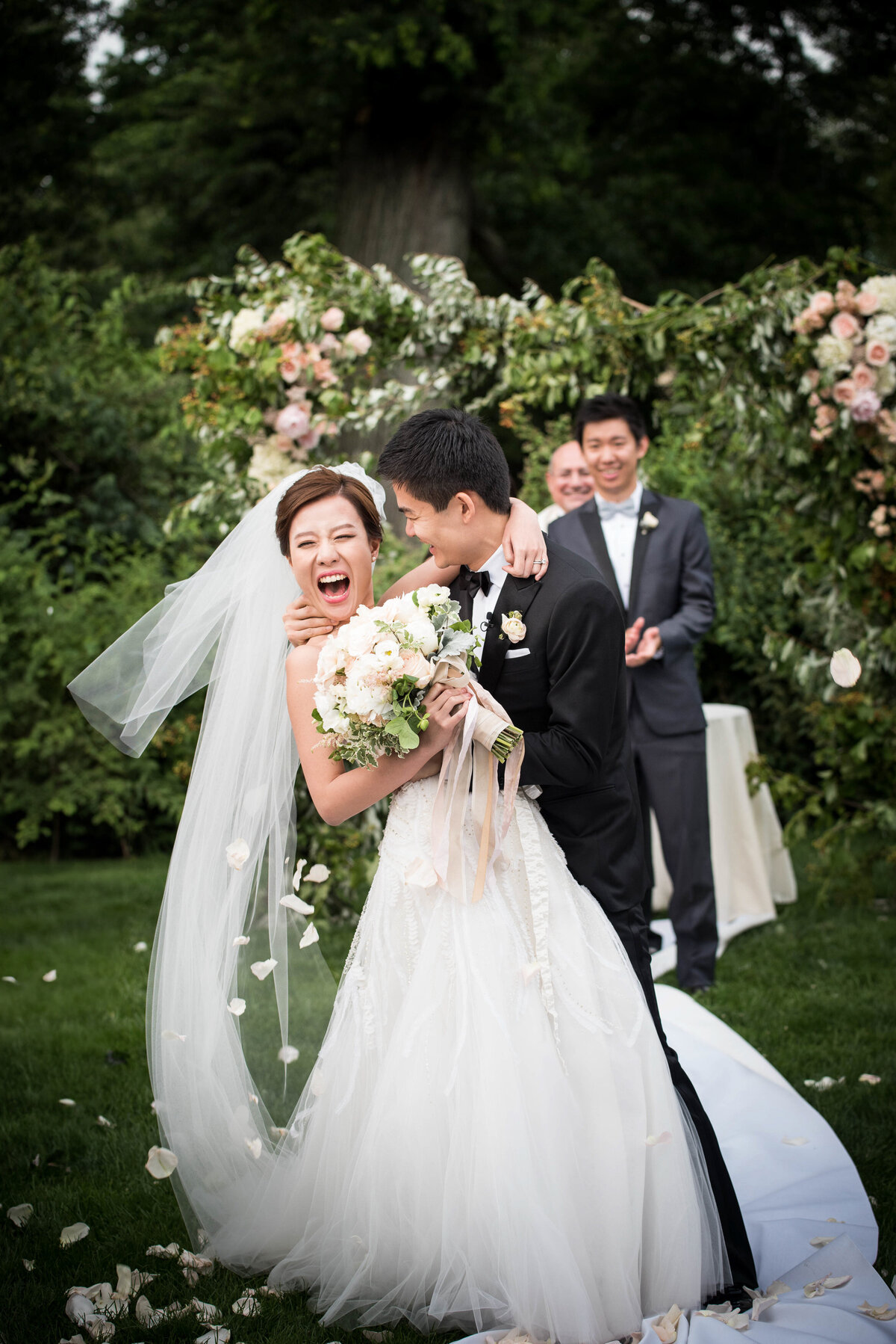 A bride smiling as her groom dips her during their wedding ceremony.