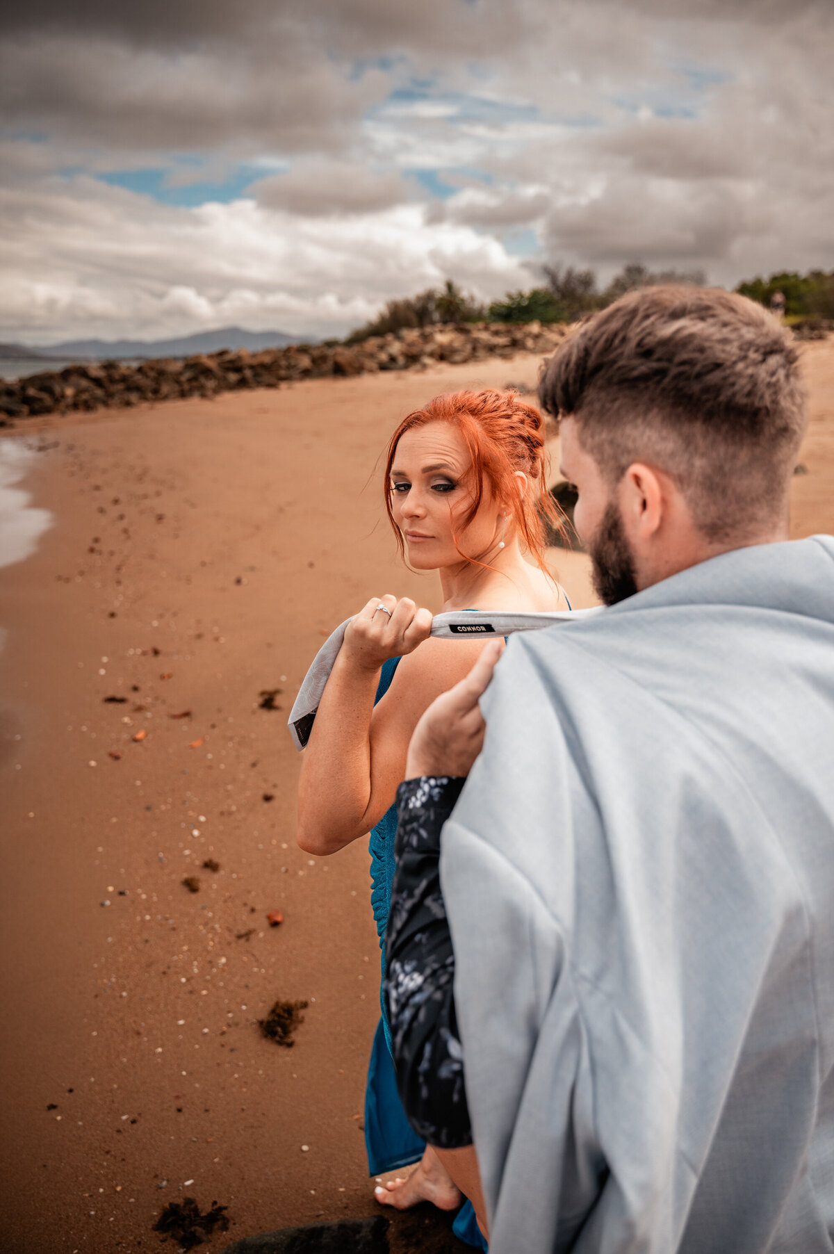 woman clutching fiance's tie and dragging him along the beach - Townsville Engagement Photography by Jamie Simmons