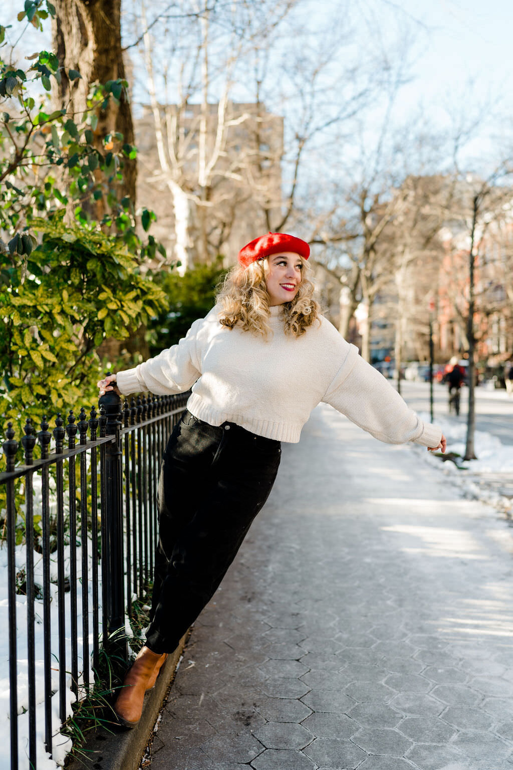 woman standing on the bottom of a fence leaning away from it while holding it with one hand