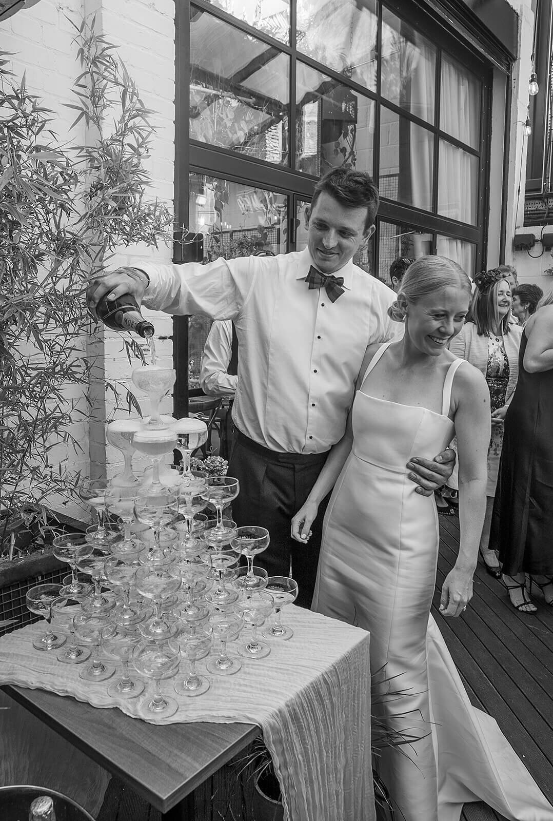Bride and groom pour champagne  on champagne tower