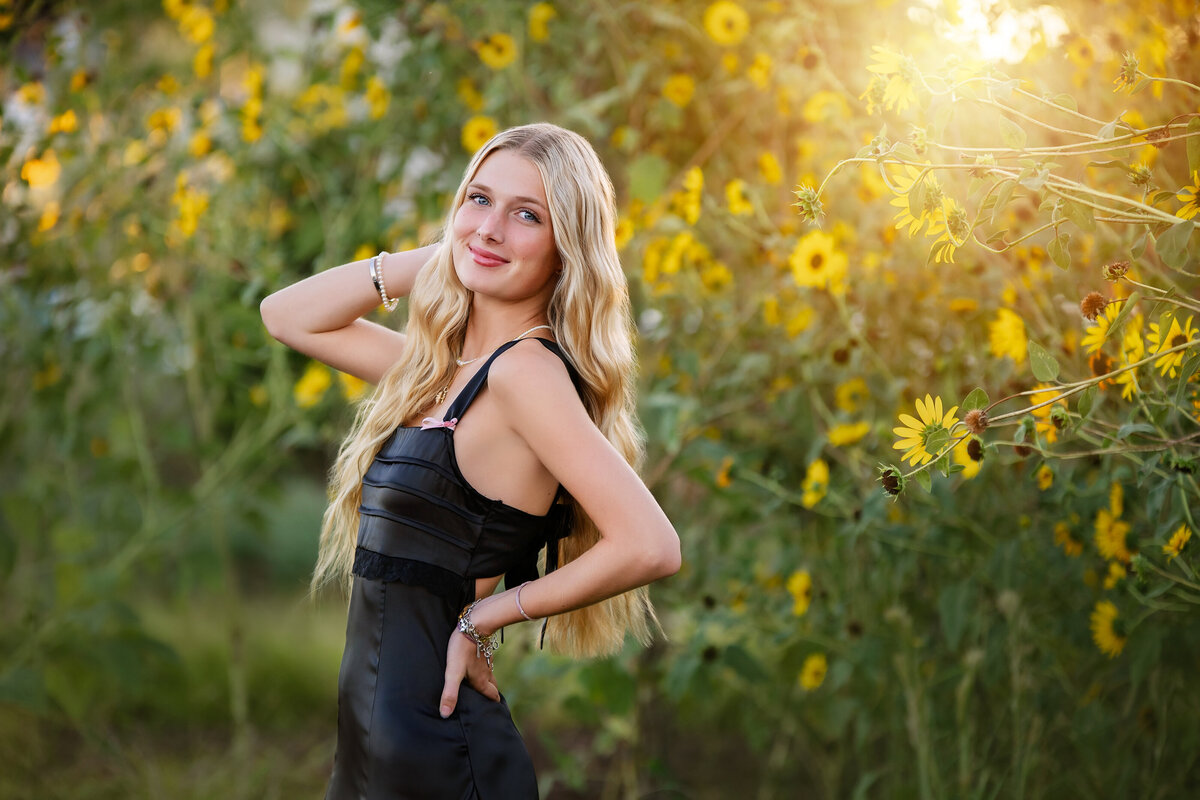 A high school senior girl poses in front of sunflowers in downtown Oklahoma City's Scissortail Park.