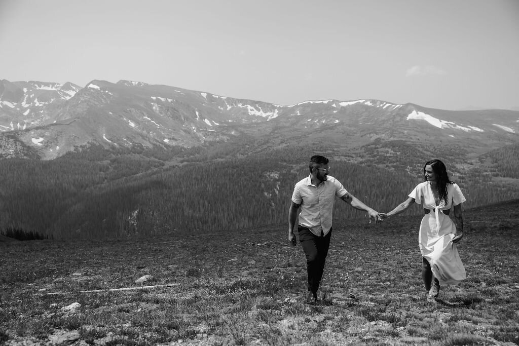 bride and groom running through wildflower meadow