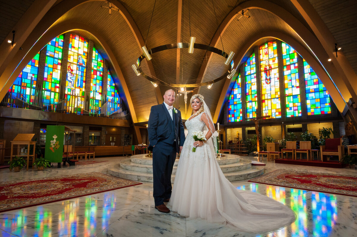 Wedding couple with stained glass windows at Saint George chruch.