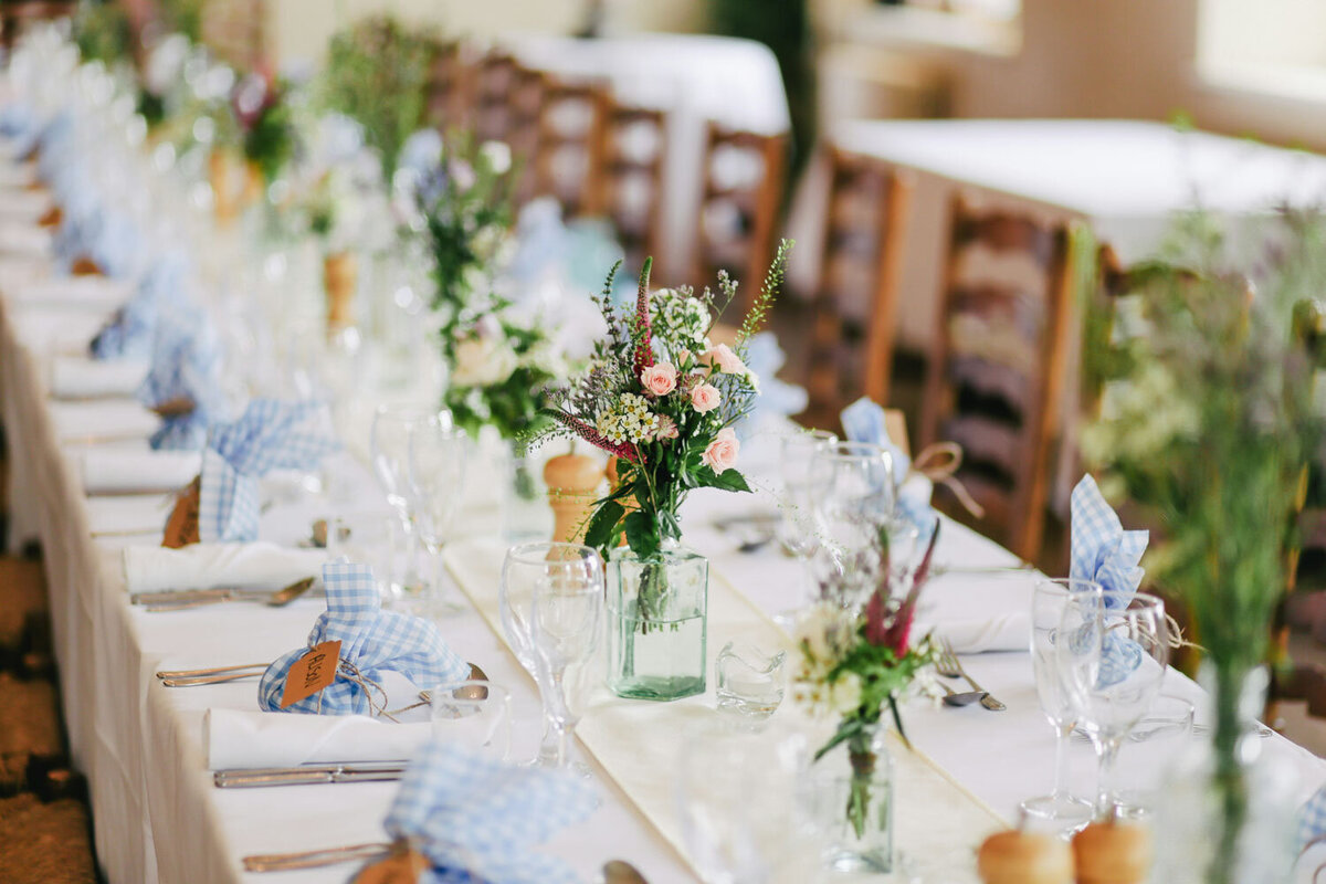 Long reception table with rustic floral arrangements and elegant settings
