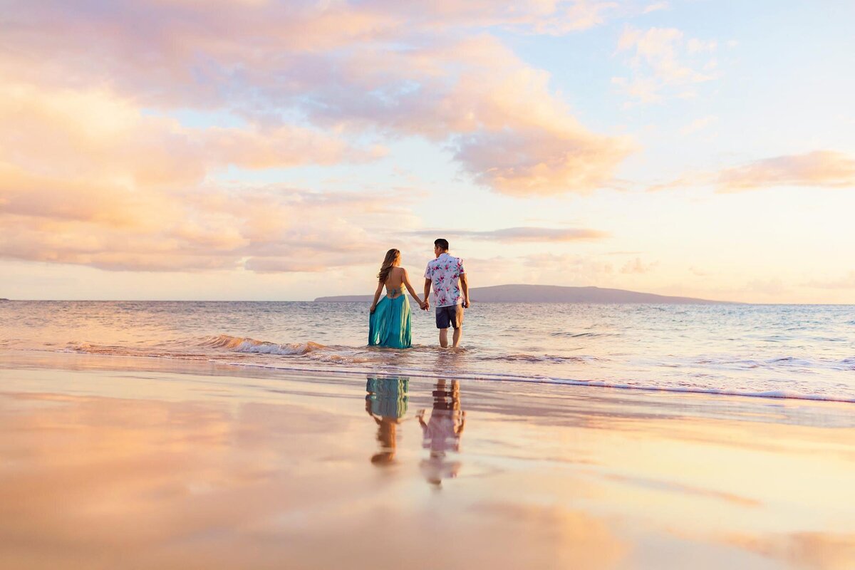 Couple holds hands and walks toward the ocean, photography by Love + Water on Maui, Hawaii