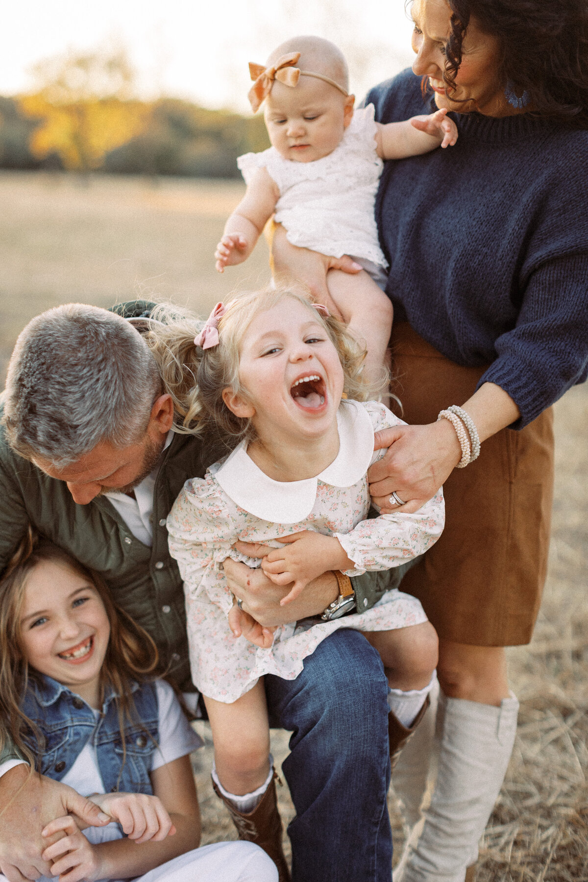 mom and dad laughing with three young girls for fall photos