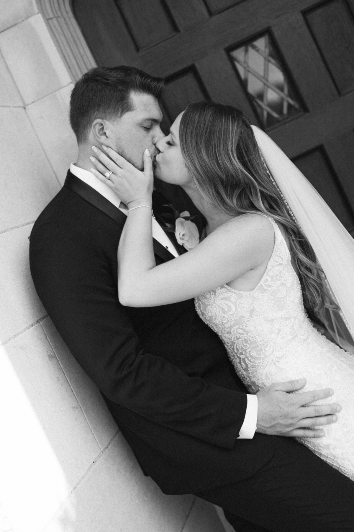 Bride and groom share romantic kiss in garden setting during wedding photoshoot.