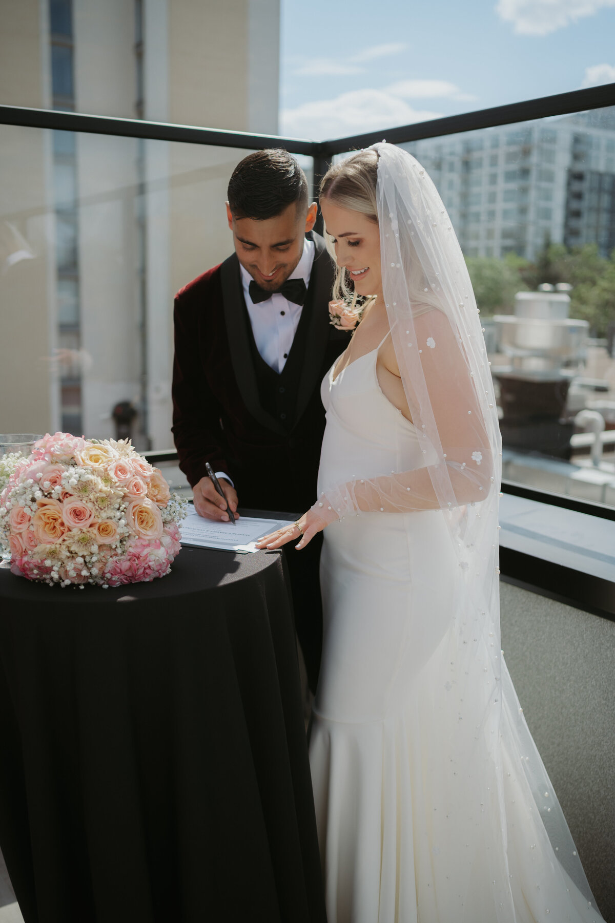 bride and groom signing wedding documents on edmonton rooftop