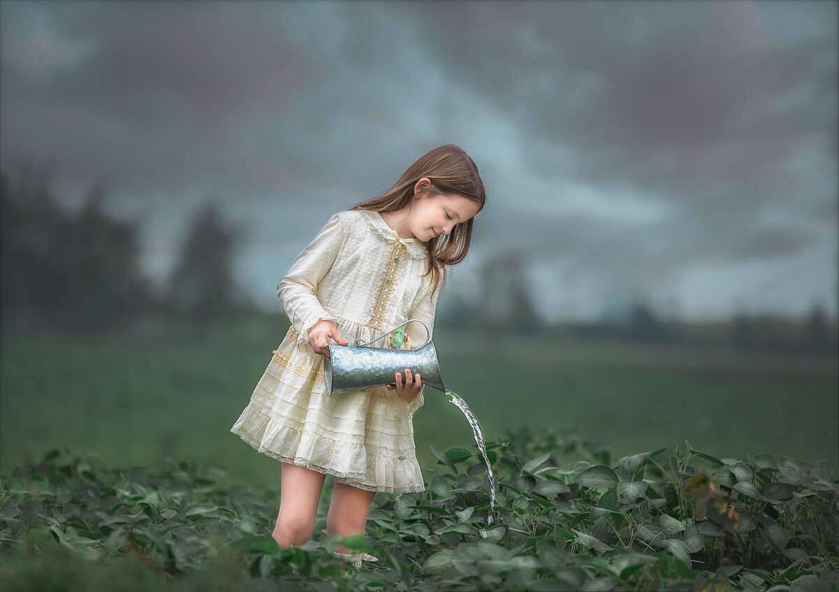 young girl watering plants during her outdoor photo session In a  North Gower Ontario  farm flied