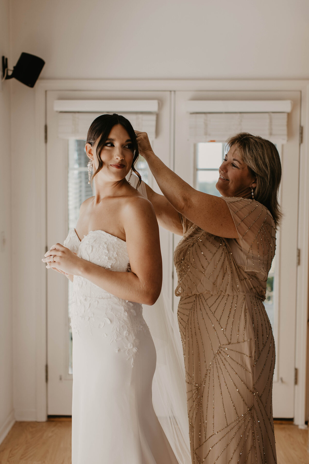 Mother of bride putting veil on her daughter. 