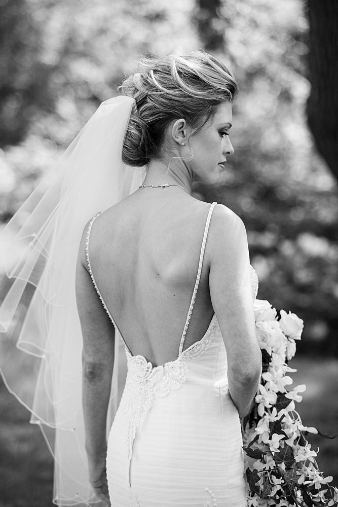 Classic bride with open-backed dress holding cascading bouquet