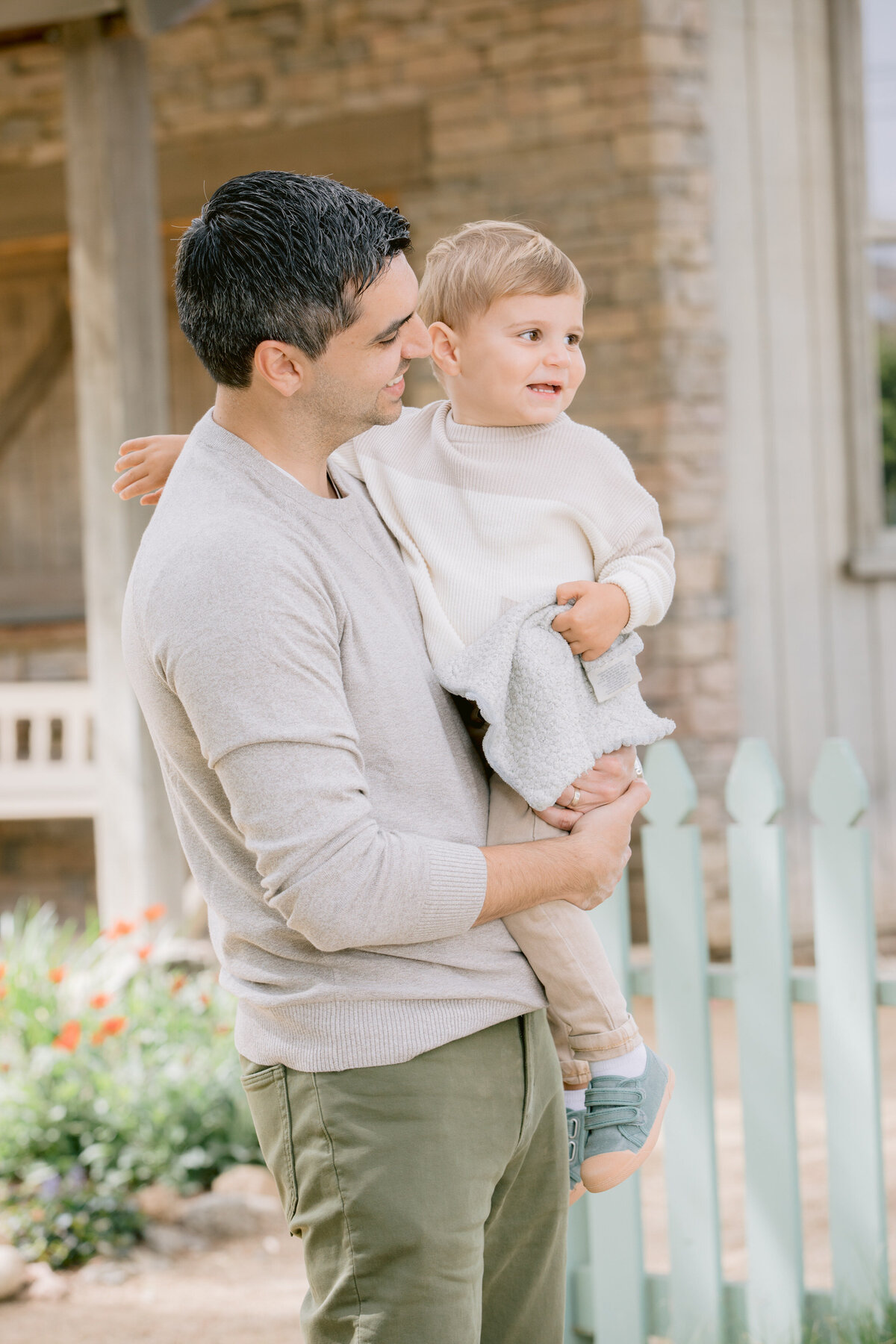 A dad holding a toddler and looking at him