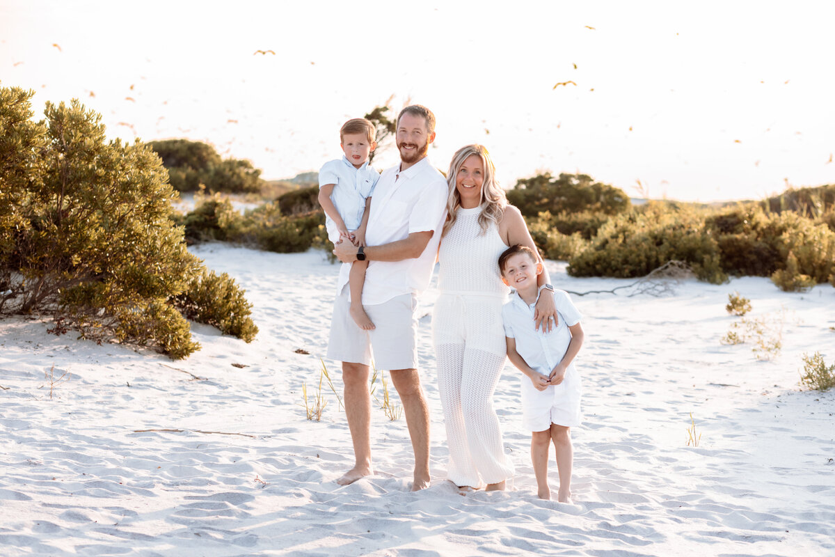 Family interacting on the beach during golden hour with seagulls flying over