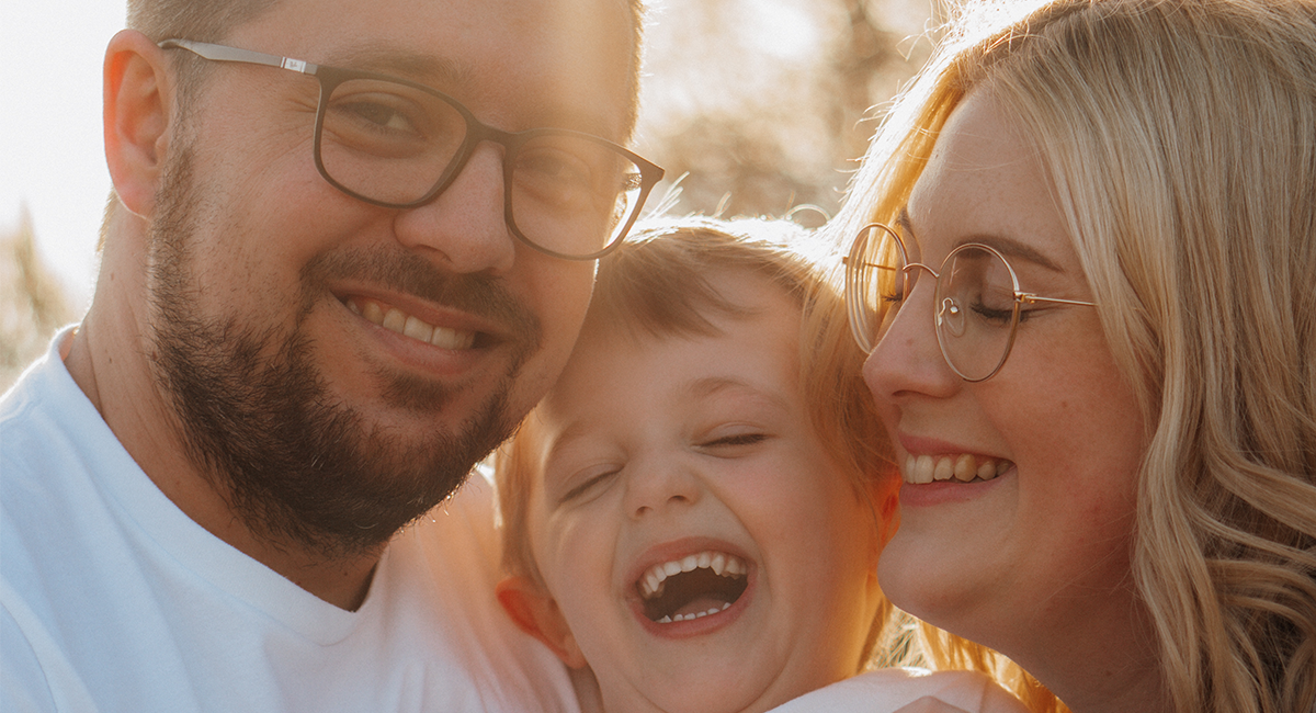 Mama, Papa und Sohn kuscheln und lachen gemeinsam