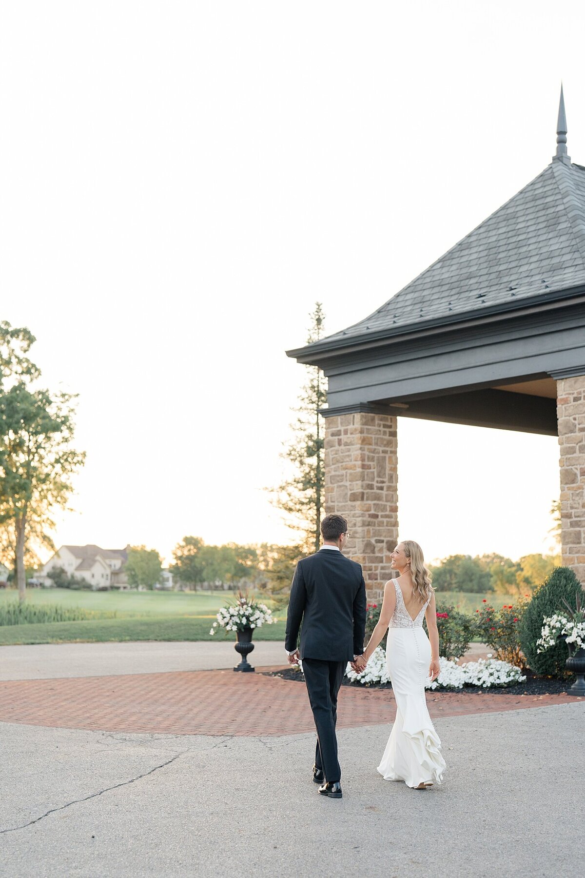 sunset wedding photos at the Pinnacle gold club with the bride and groom holding hands and walking across a patio together