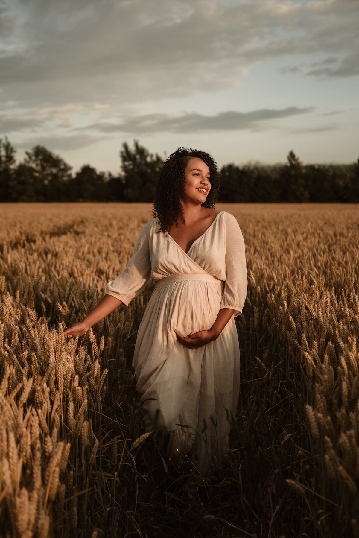 zwangere vrouw in graanveld tijdens golden hour