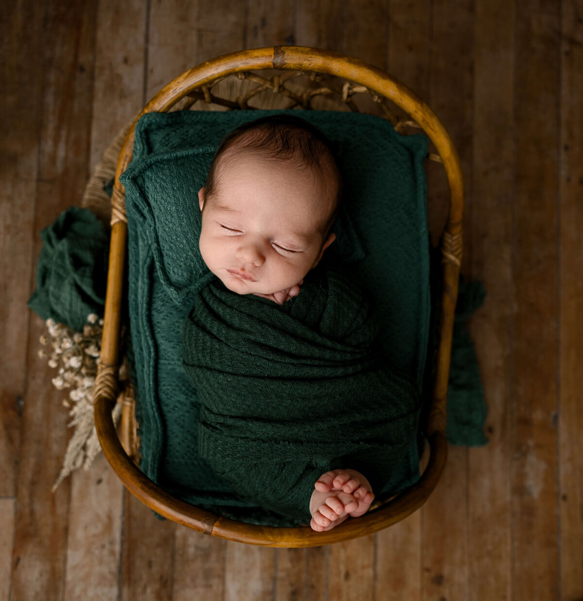 Photo of a baby boy in forest green in a criss cross wrap with toes sticking out