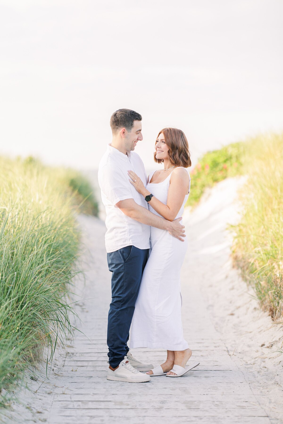 Couple hugging in between sand dunes at Wingaersheek Beach