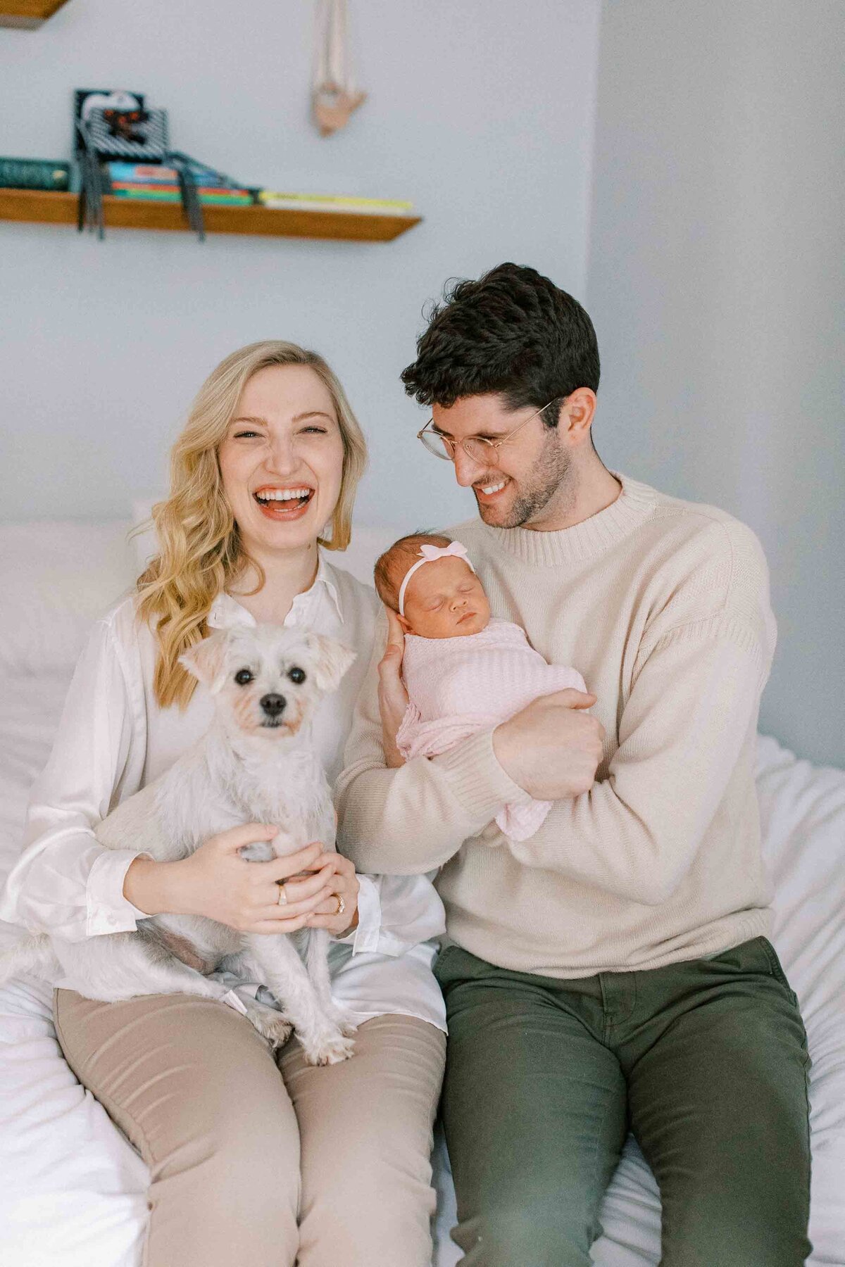 new parents holding their dog and new baby